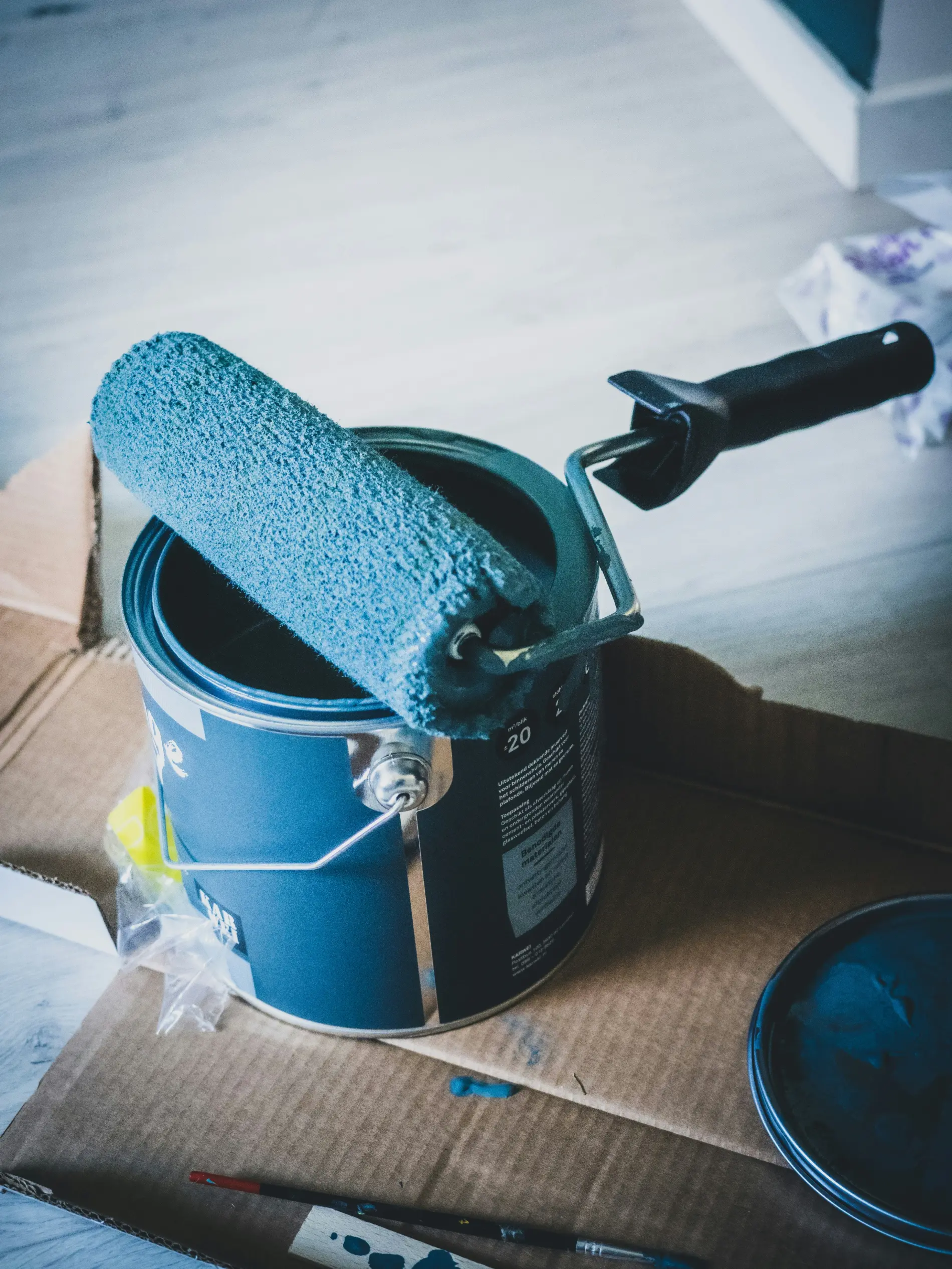 Rouleau imbibé de peinture reposant sur un pot bleu
